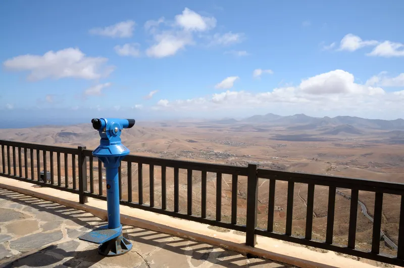 Münzfernglas auf einem Aussichtspunkt auf Fuerteventura mit weitem Panoramablick über die karge Insellandschaft.