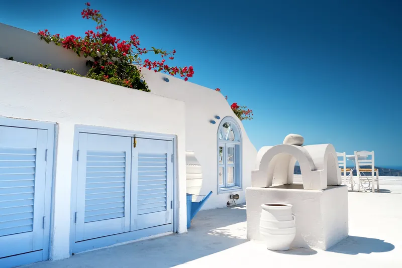 Weiß getünchte Häuser mit blauen Fensterläden und blühender Bougainvillea auf Santorin.